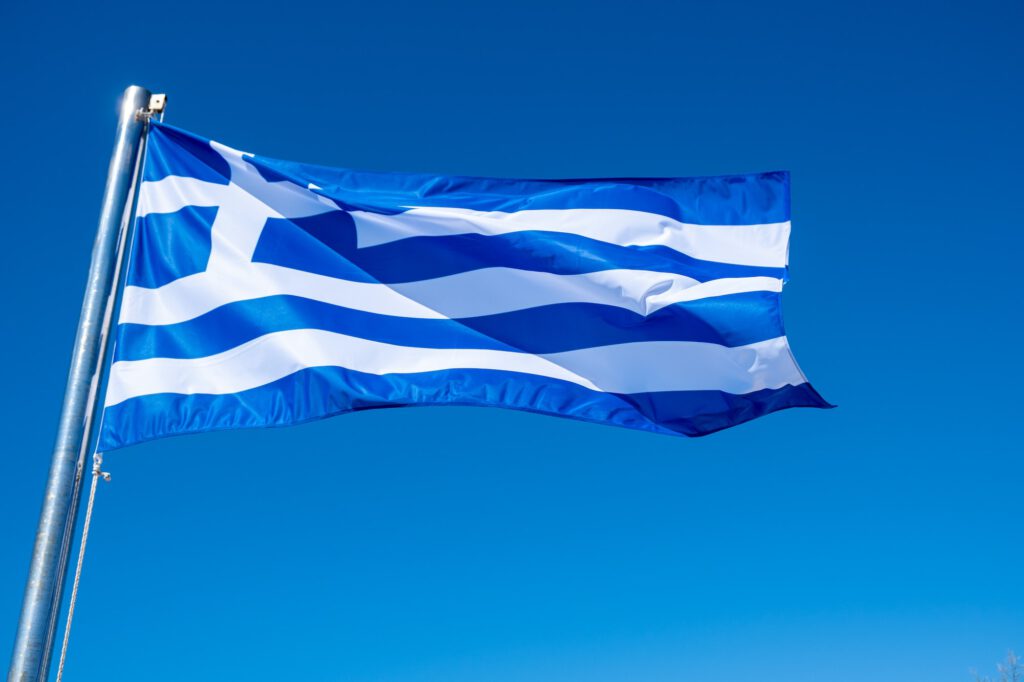 Greek flag waving against blue sky background.